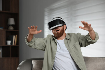 Emotional man using virtual reality headset on sofa at home