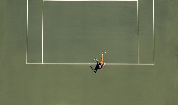 Aerial view of tennis player serving on court during match on a sunny day