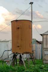 Large rusty water tank on supports in the backyard