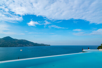 Obraz premium Swimming pool with stair on top of roof deck building looking at view tropical sea ,Luxury beach villa house with sea view swimming pool in modern design,Summer Vacation and travel background concept