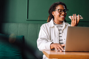 Happy black woman using smartphone and laptop