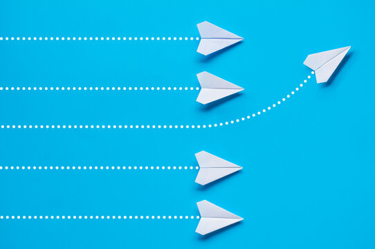Top view of white paper airplanes with one flying to the other director. Leadership or courage concept