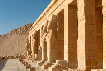 Fototapeta premium The columns of the temple of Hatshepsut in Luxor are adorned with statues of the pharaoh. This architectural masterpiece is a testament to the rich history and artistic achievements of ancient Egypt.