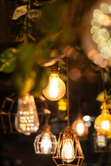Classic designed ceiling lighting bulb with iron cage, it glowing in orange warm light shade. Object for interior decoration, close-up with selective focus.