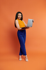 Fototapeta premium A stylish woman presents her laptop with a vibrant smile.