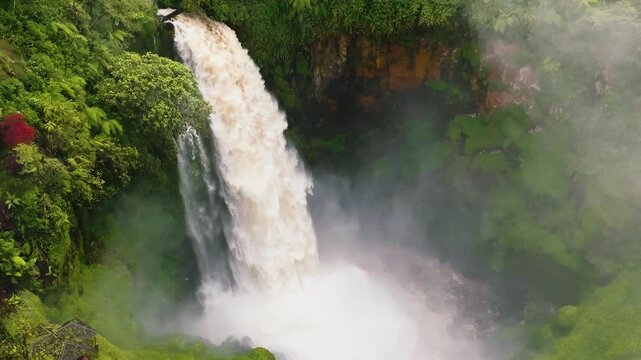 Aerial drone of Telun Berasap Falls in mountain jungle. Waterfall in slow motion. Sumatra, Jambi, Indonesia.