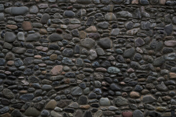 grey wall is decorated with small round pebble stones - natural eco building material. exterior,...