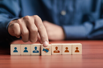 Businessman arranging wooden blocks with handshake icon and people icon for business joint venture...