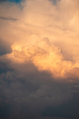 Big white clouds floating in the sky, vertical shot. Warm sunlight on beautiful gentle clouds, concept of calmness and greatness of nature