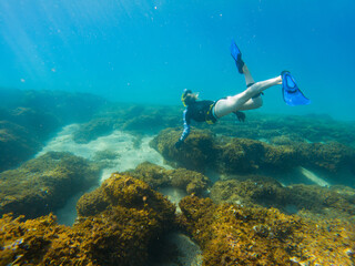 A woman is swimming in the ocean wearing a blue wetsuit