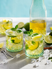 Lemonade with lemon and mint. Cocktail, ice tea in glasses and jug. Grey background.