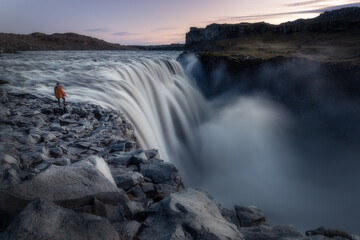 Lone hiker on the edge of Detifoss waterfall in Iceland
