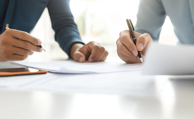 Two people writing and reviewing documents together at a desk.