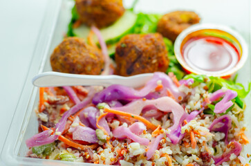 A salad with meatballs and a dipping sauce