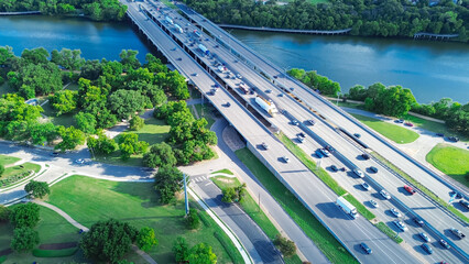 Highway 35 across Colorado River in downtown Austin, riverside boardwalk cut thru lush greenery trees bank shore in South side of city urban core to Travis Heights community neighborhood, aerial