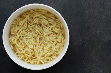 Top view of boiled instant noodles cup on table black background