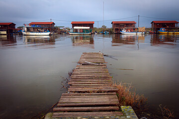 Tranquil afternoon at Delta Aliakmona, Greece, featuring rustic fishing huts and a weathered wooden...