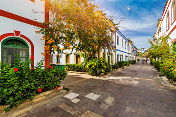 Street with blooming flowers in Puerto de Mogan, Gran Canaria, Spain. Favorite vacation place for tourists and locals on island. Puerto de Mogan with lots of bougainvillea flowers, Canary Island.