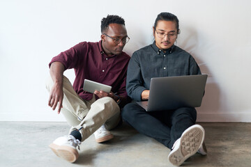 Teamwork, laptop and tablet of business people on floor, planning and research for startup in office. Career, men or web developer with technology for layout design, solution and creative agency