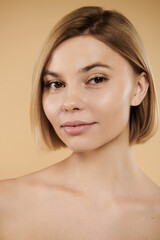 Appealing woman looking at camera on pastel backdrop.