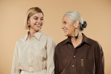 A mature woman and her adult daughter share smiles and joy in coordinated outfits.