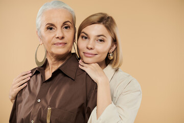 A mature woman embraces her adult daughter, showcasing their close relationship.