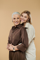 A mature woman and her daughter share a joyful embrace, smiling warmly.