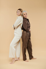 Two women share a moment, standing back to back in coordinated outfits.