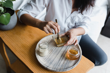Latin woman applying facial mask on face for exfoliation with honey at home in Mexico Latin America, hispanic people	