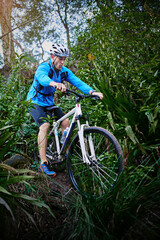 Naklejka premium Man, sports and mountain bike in forest with helmet, dirt and off road for fitness, adventure and health. Cyclist, bicycle and cycling outdoor in nature for workout, exercise and training with trees