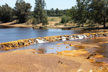 paisaje de rio tinto con arboleda y cascada por su paso por Niebla en Huelva, España