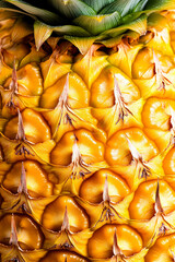 Detailed shot of a pineapples skin showcasing the tough spiky texture with golden yellow and brown hues 