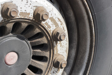 Rusty truck wheel rim and cracked tire. Grunge detail truck tyre. Parcel delivery industry. Weathered and worn vehicle parts. Damaged car wheel. Dangerous to drive. Rusty bolts in a circle shape.