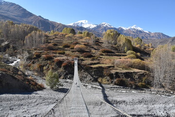 A high suspension bridge hanging over a valley in Mustang, Nepal