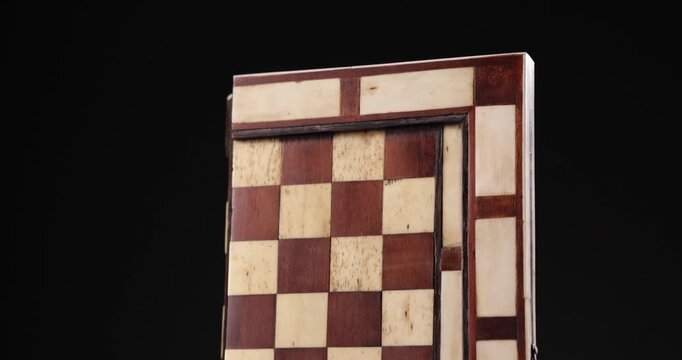 Detailaufnahme Rotation eines Backgammon und Schach Spielbretts vor schwarzem Hintergrund