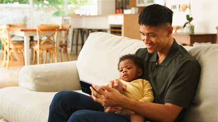 Caring Father Engaging With Baby on Tablet in Cozy Living Room