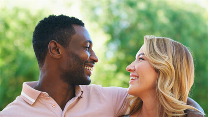 Obraz premium Couple Smiling at Each Other in Natural Setting During Sunny Afternoon