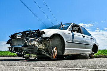 A damaged silver car sits idle on the roadside awaiting help