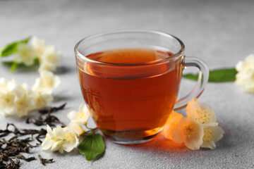 Hot jasmine tea in cup and flowers on light grey table