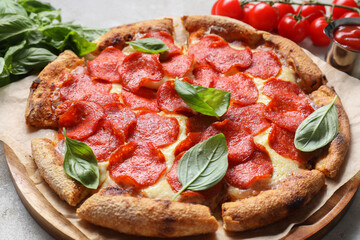 Tasty pepperoni pizza with basil and tomatoes on table