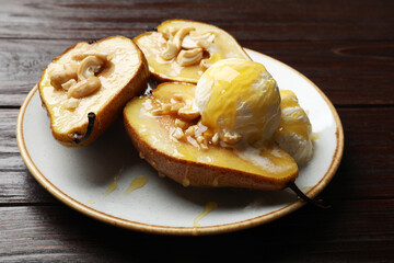 Delicious baked pears with nuts, ice cream and honey on wooden table, closeup