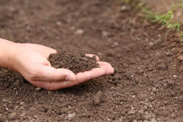 Woman holding pile of soil outdoors, closeup. Space for text
