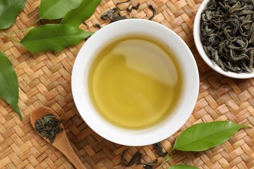 Refreshing green tea in cup, spoon and leaves on table, flat lay