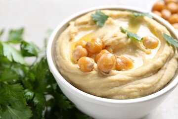 Delicious hummus with olive oil and chickpeas on light table, closeup