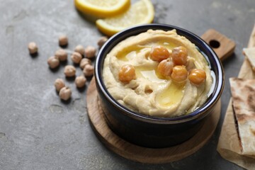 Delicious hummus with olive oil and chickpeas in bowl on grey table