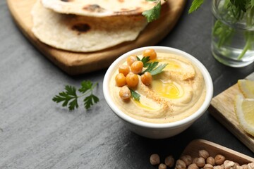 Delicious hummus with olive oil and chickpeas in bowl served on grey table