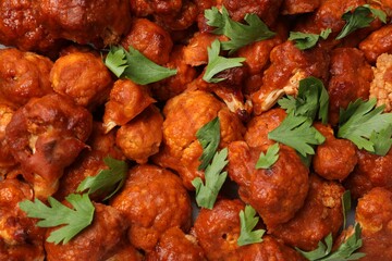 Baked cauliflower buffalo wings with parsley as background, top view