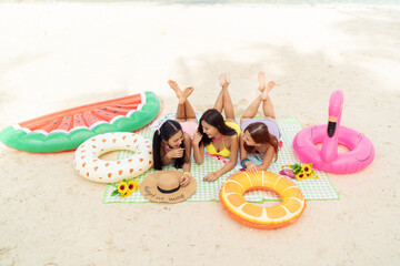 Three beautiful Asian girl friends in colourful bikinis having a day out by the beach