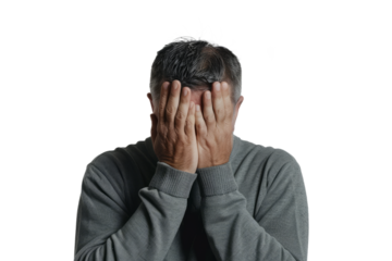 Man with his face partially obscured by his hands, showing a moment of overwhelm, on a white backdrop.