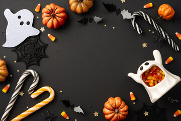 Halloween background featuring candy corn, mini pumpkins, ghosts, bats, and candy canes on a black...